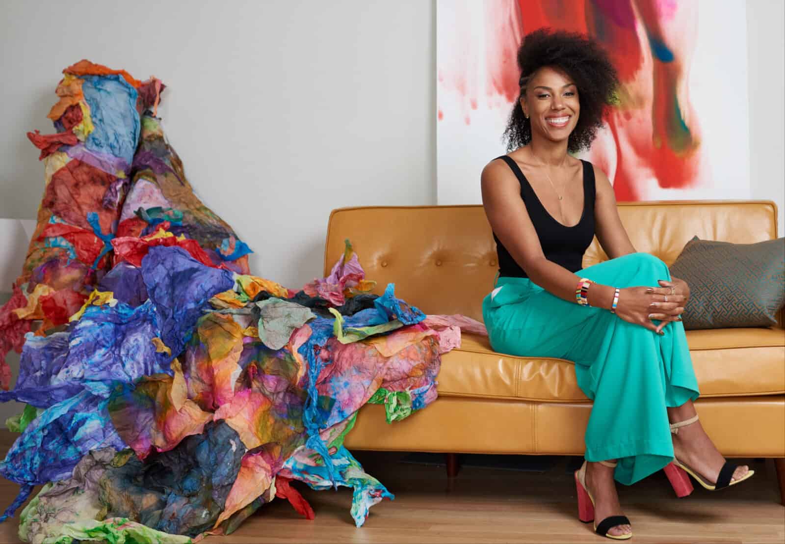 Acclaimed artist Maya Freelon sits beside a bright waterfall of her tissue ink prints. Press image courtesy of WCMA and the artist