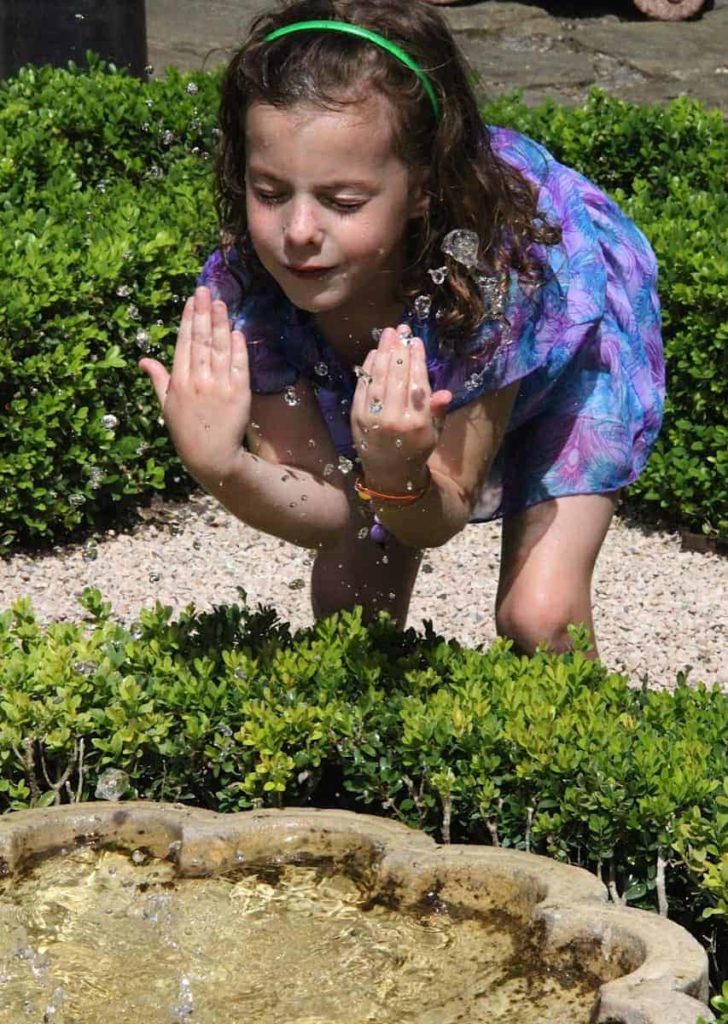 A young visitor cools off near a fountain at Naumkeag in Stockbridge. Photo by Susan Geller