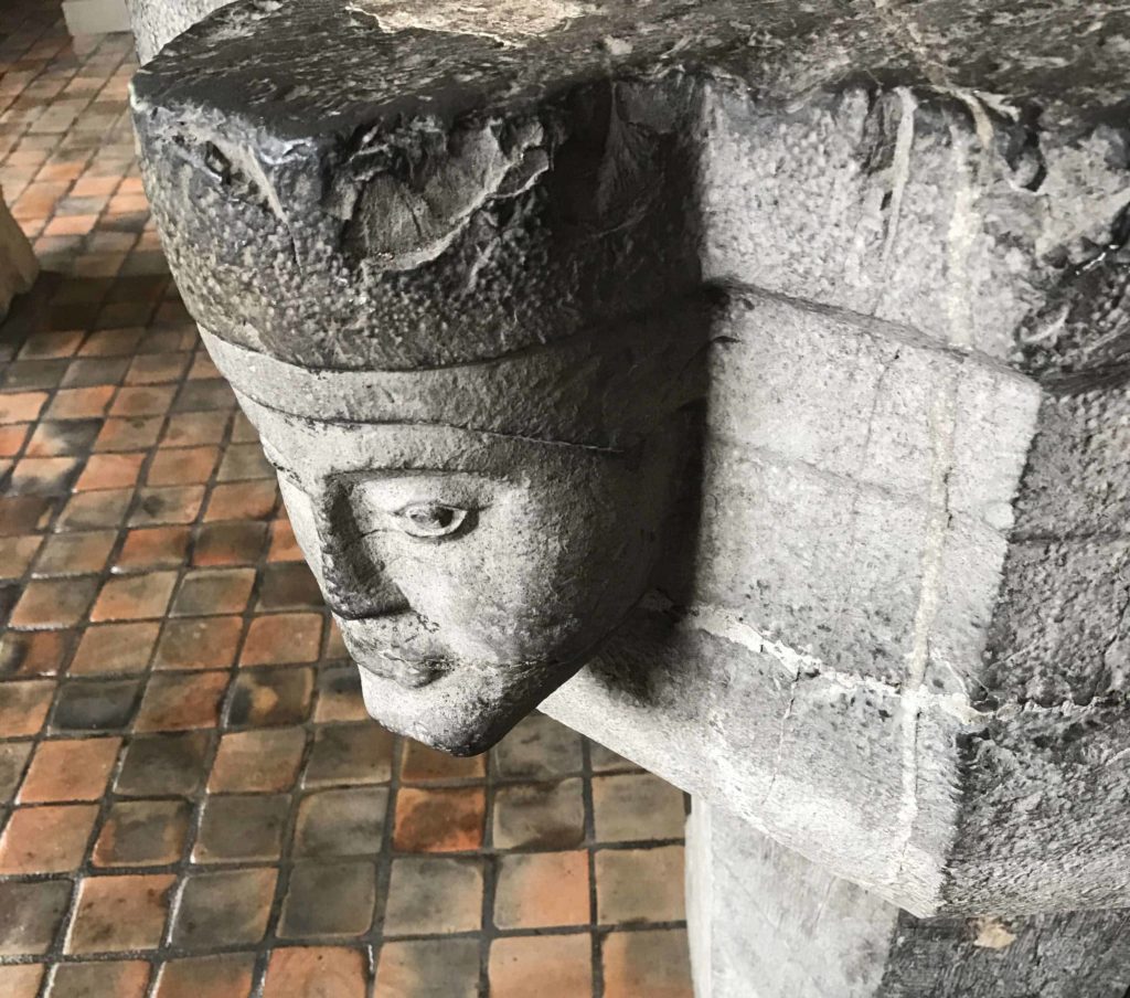 Faces peer out from a stone baptismal font.