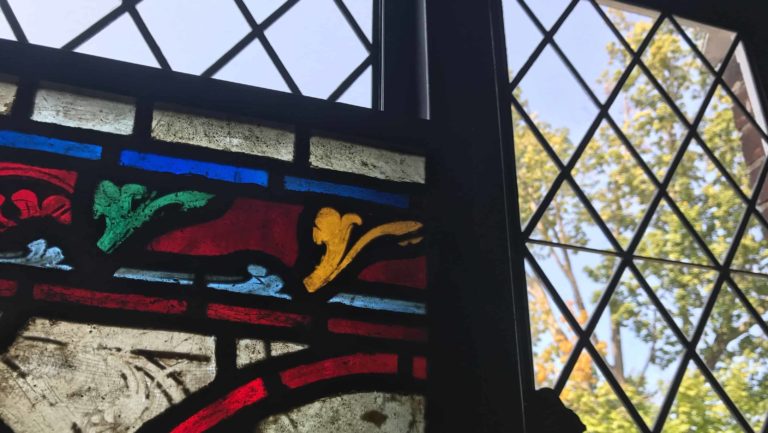 An inset stained glass panel, a Grisaille from France, shines among diamond panes.