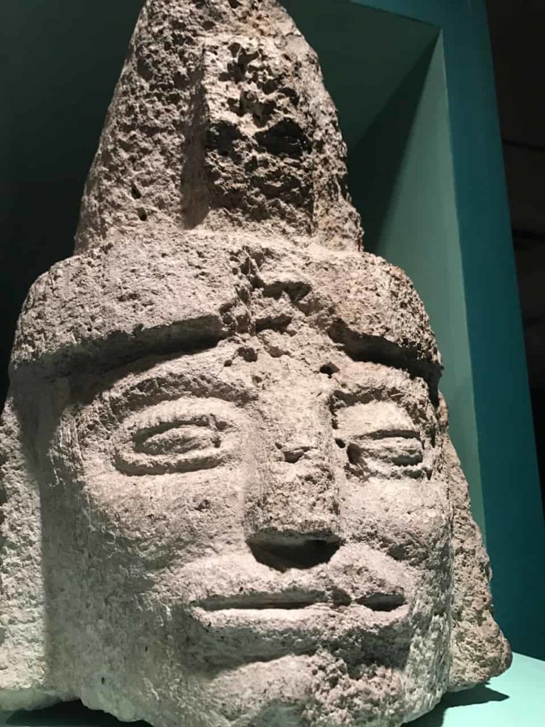 A limestone human figure wears a peaked headdress and sits on a central pillar, recalling the position it would have held on the wall of a Mayan temple 1,200 years ago. Photo by Kate Abbott
