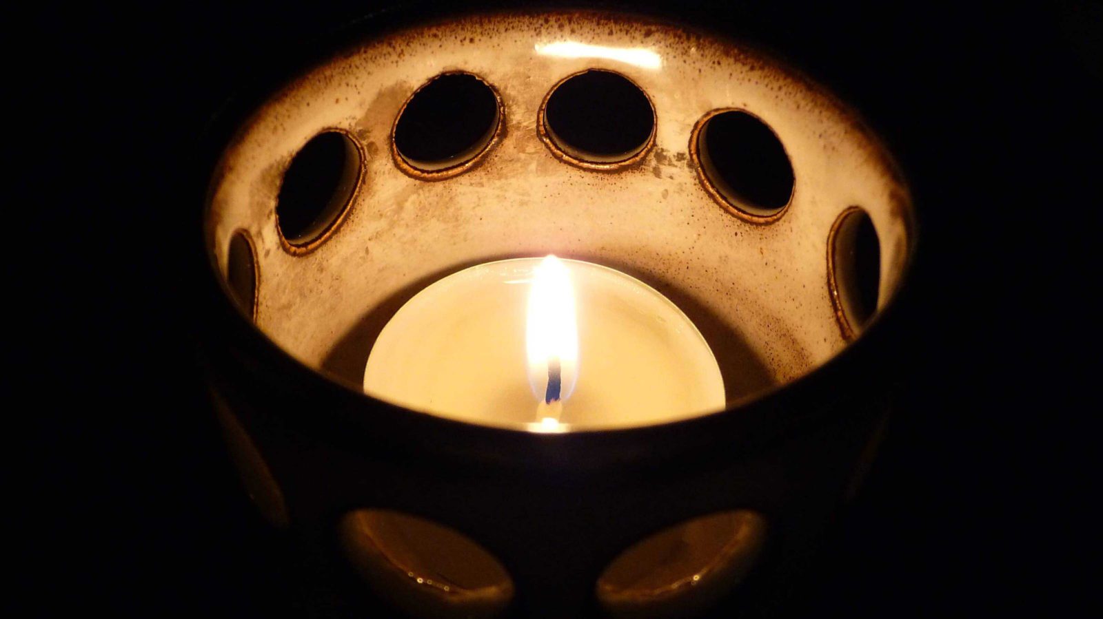 A candle burns in the dark.