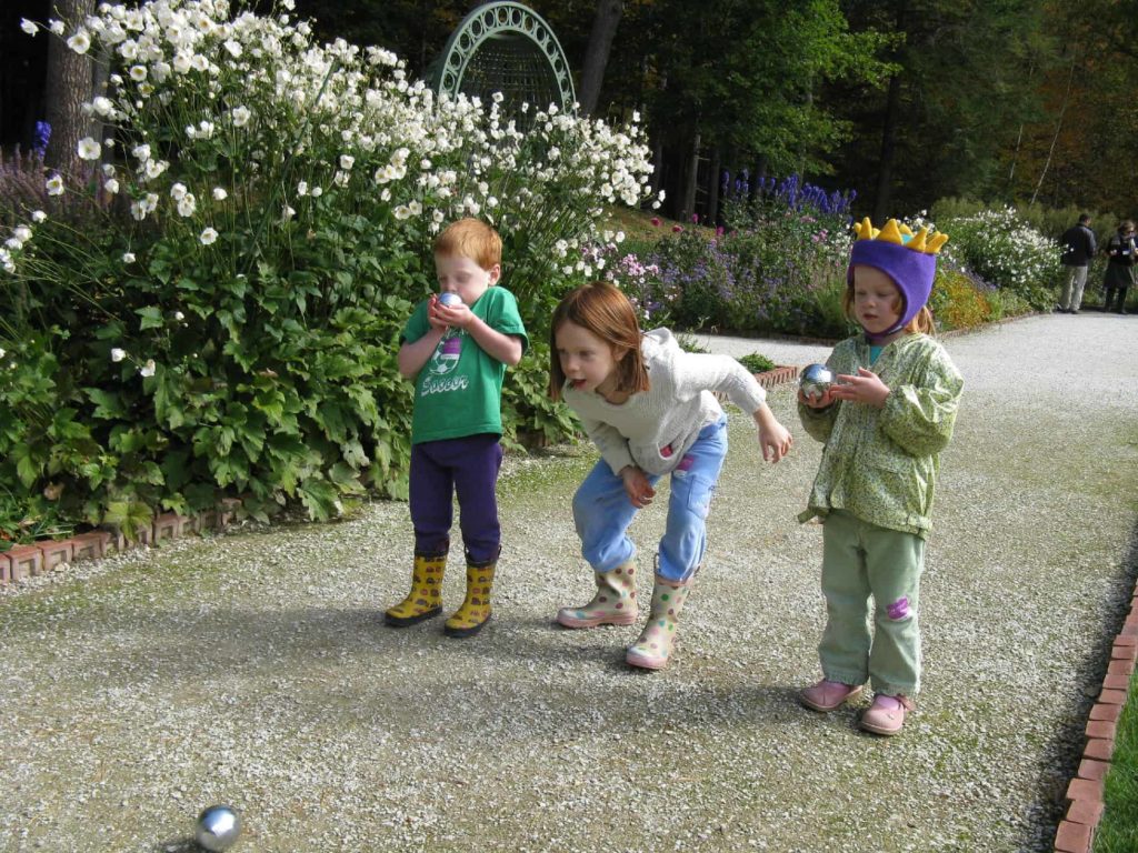 Young visitors play Petanque in Edith Wharton's gardens at The Mount on a summer day.