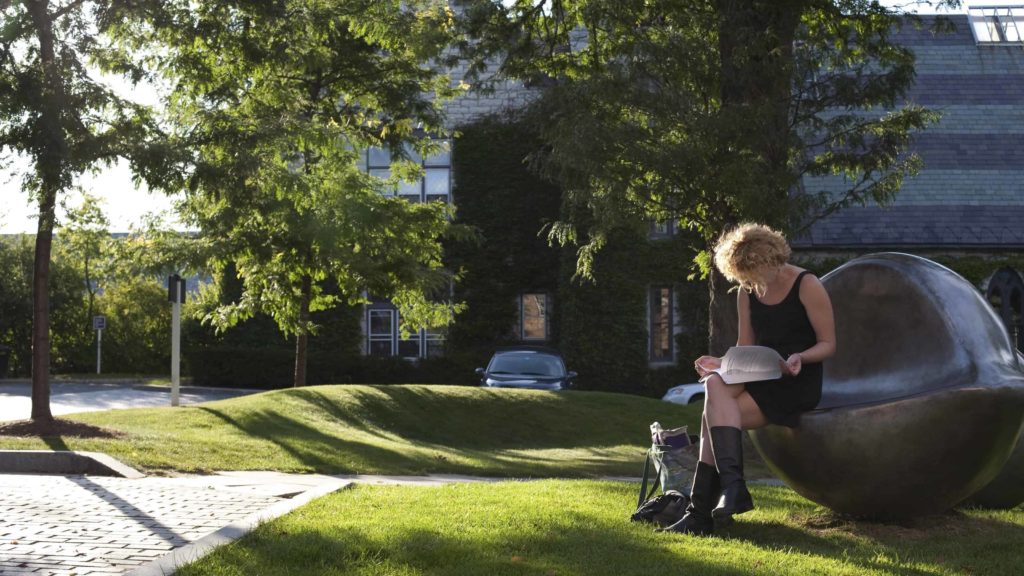 A reader sits on one of Louise Borgeois' giant glowing eye sculptures outside of the Williams College Museum of Art.