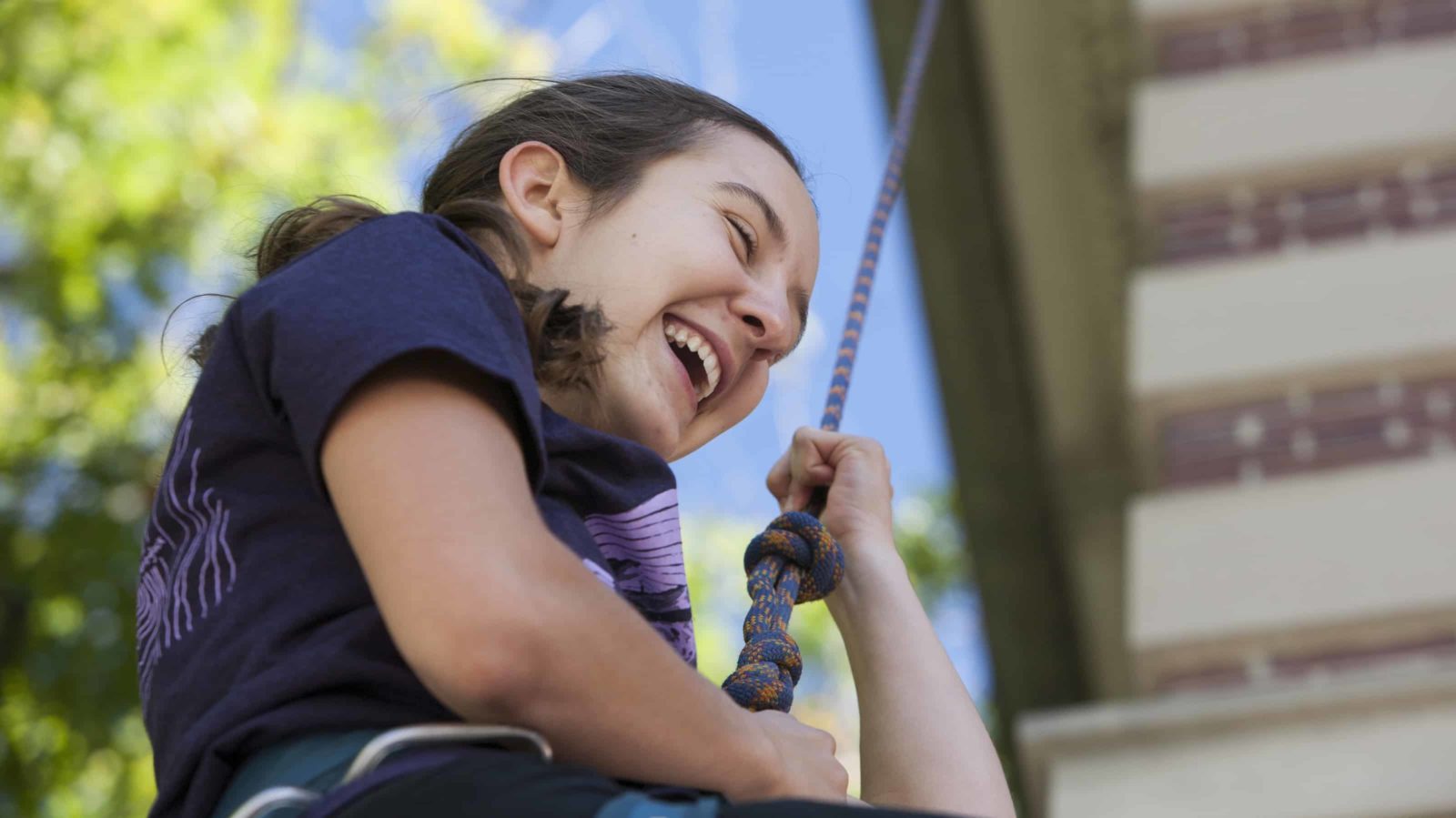 A student rappels from a college building on Mountain Day at Williams College. Students celebrate a fall day with music and outdoor activities.