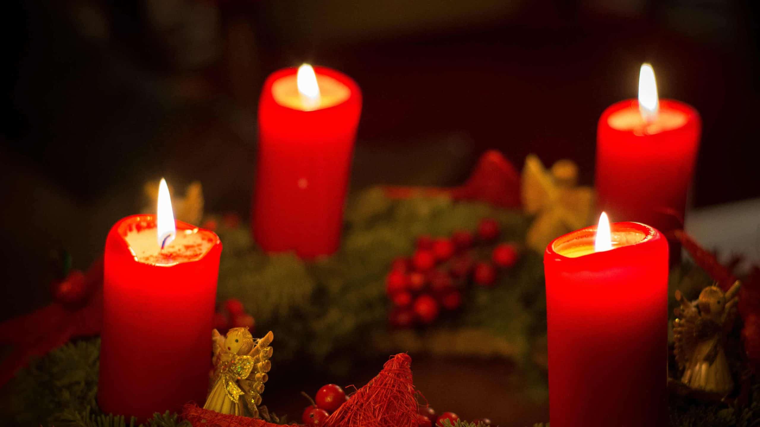 Candles burn with evergreens and red berries.