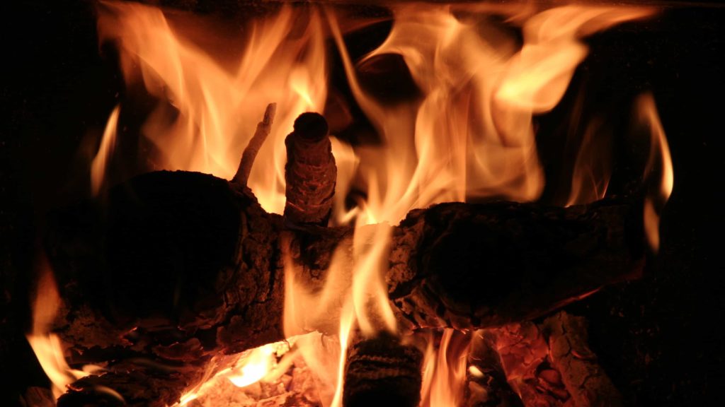 A wood fire blazes in the hearth. Courtesy creative Commons photo.