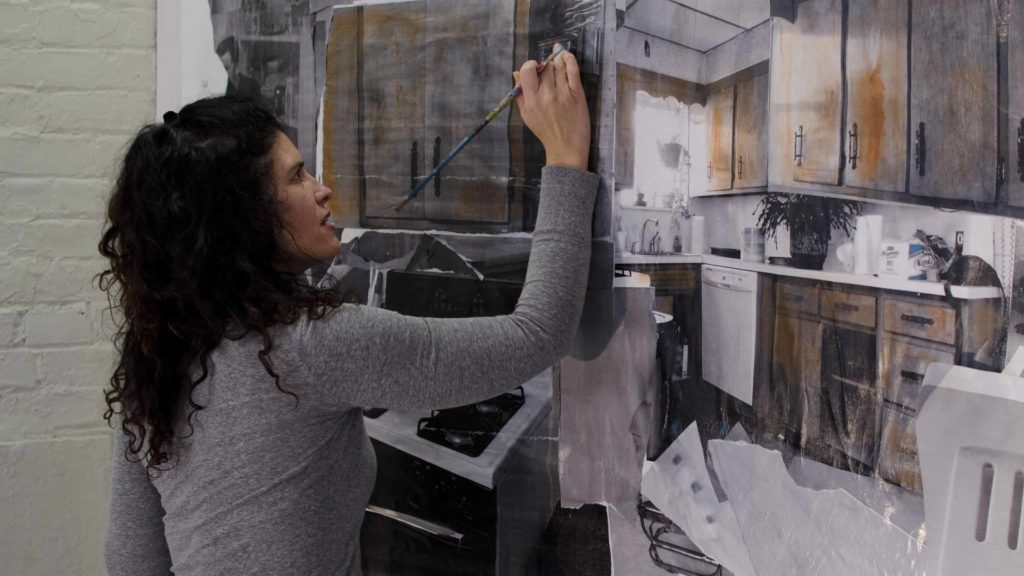 An artist in residence paints in a studio at Mass MoCA.