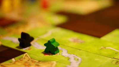 Game pieces rest on a tile game board like Carcassonne.