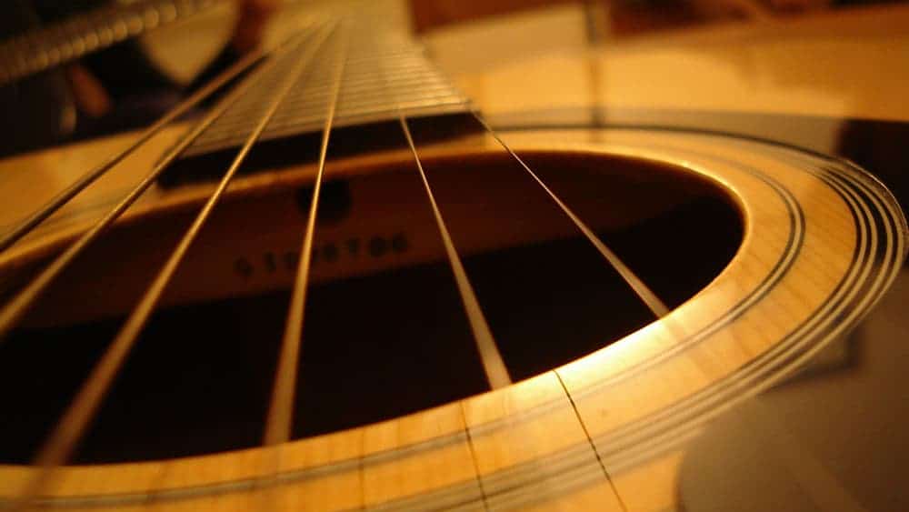 Light slides down the strings of an acoustic guitar.