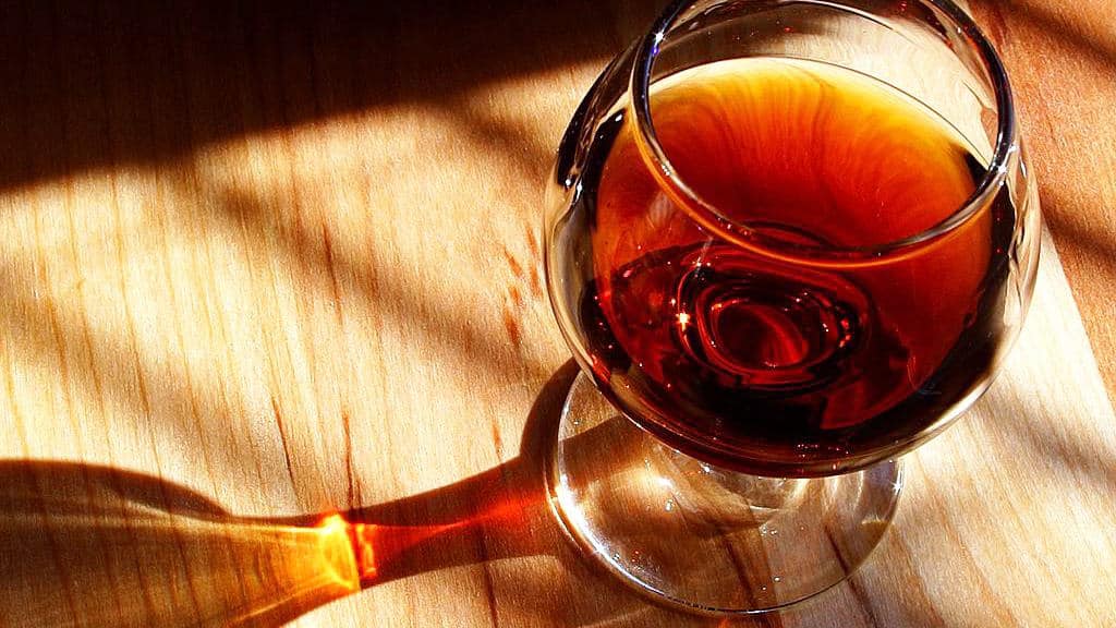 A glass of port wine gleams amber in sunlight.