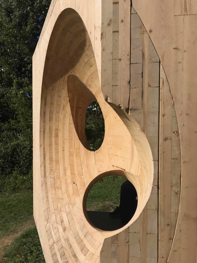Steven Holl's wooden curves in 'Obolin' stand at the corner of the field overlooking Art OMI's architecture exhibits.