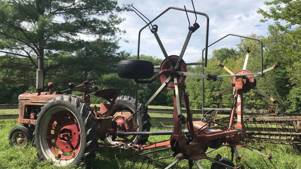 A venerable tractor hitched to a tedder waits to tend a hayfield above the Clark Art Institute.