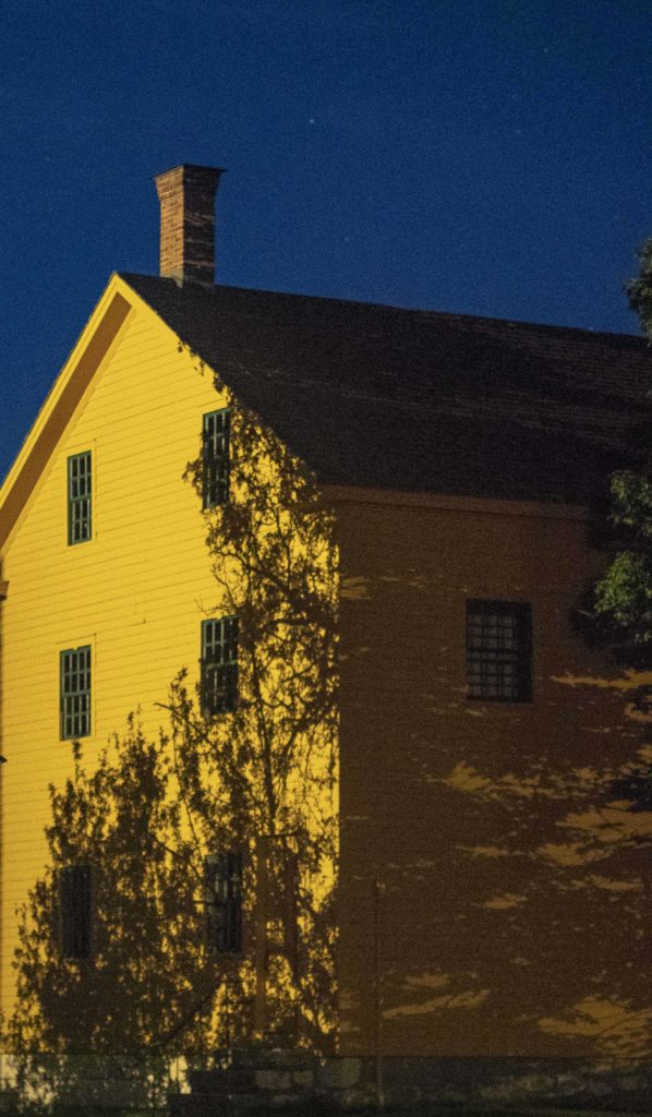 Shadows fall on a yellow house at Hancock Shaker Village.