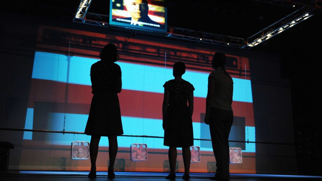 Members of Sojourn Theatre's ensemble cast look up at TV monitors of political ads as they pre-set on the stage for the interactive play 'The Race' at Georgetown University's Gonda Theatre in Washington.