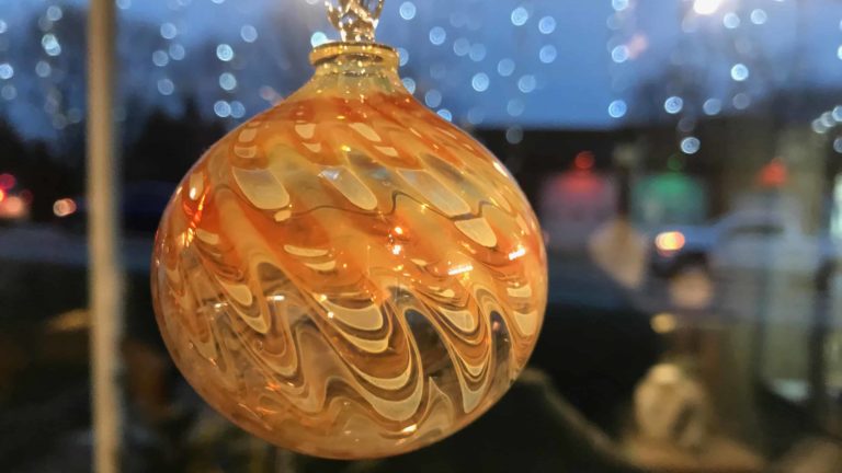 A handmade glass ornament glows warmly at Cheshire Glassworks.