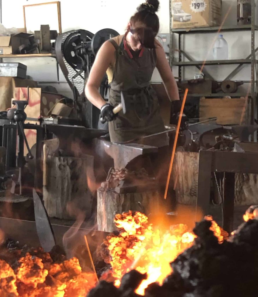 A blacksmith works at the forge at Salem Art Works.