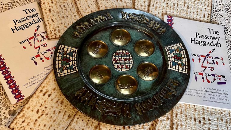 A Seder plate sits in a ring of matzah by a Haggadah for Pesach (Passover).