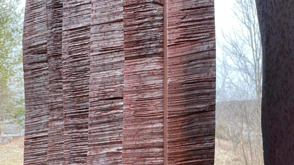 Metalwork with a patina of rust shows striations like wood grain against the sky at Turn Park.