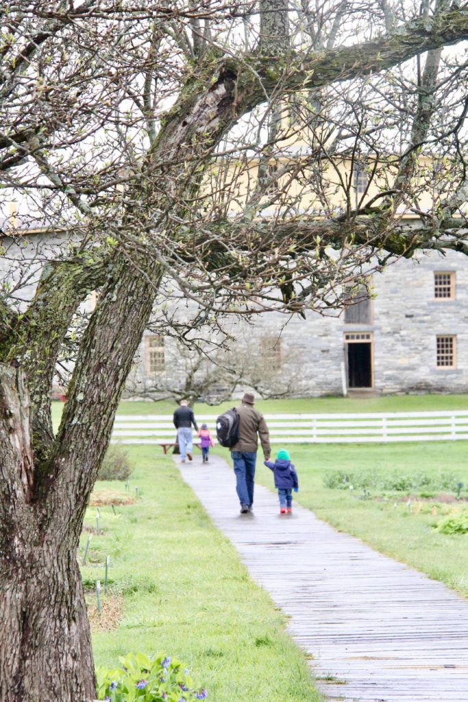 Families walk up the boardwalk toward the Round Stone Barn on an April day.