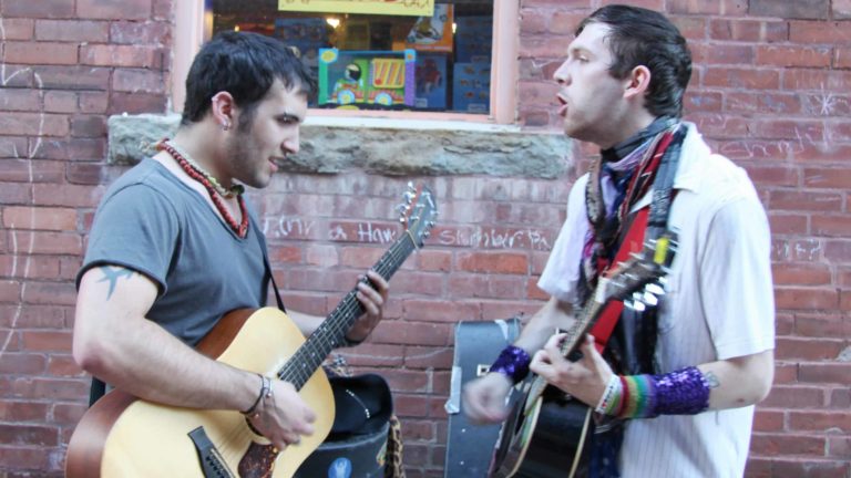A guitar duo plays together on a Berkshire sidewalk on a warm night.