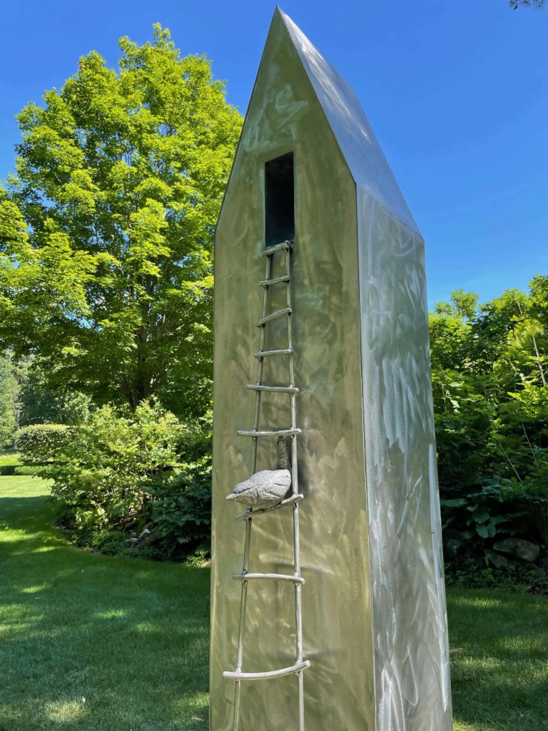 A sculpted songbird lights on the ladder of Kate Winn's aluminum Birdhouse at The Mount.