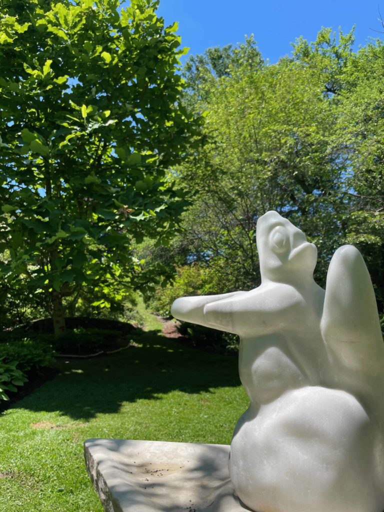 Ian Swordy's curved stone sculptures of squirrel-like creatures catch the light at the Berkshire Botanical Garden.