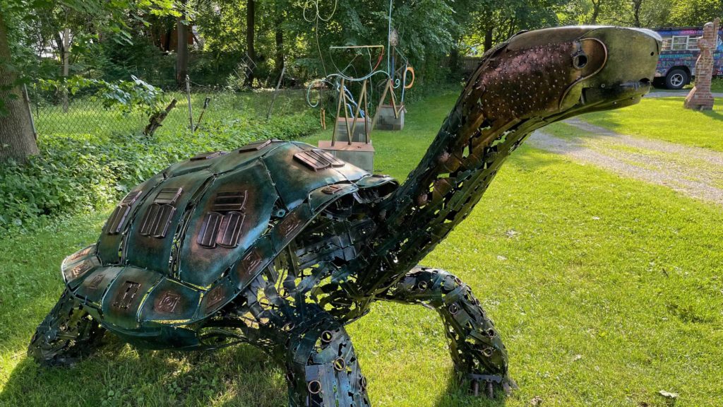 Lonesome George, a giant coppery turtle, a metal sculpture by José Criollo, stands in the park across from the Vermont Arts Exchange in the North Bennington Outdoor Sculpture Show.