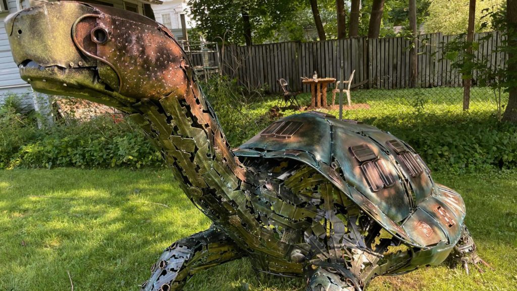Lonesome George, a giant coppery turtle, a metal sculpture by José Criollo, stands in the park across from the Vermont Arts Exchange in the North Bennington Outdoor Sculpture Show.