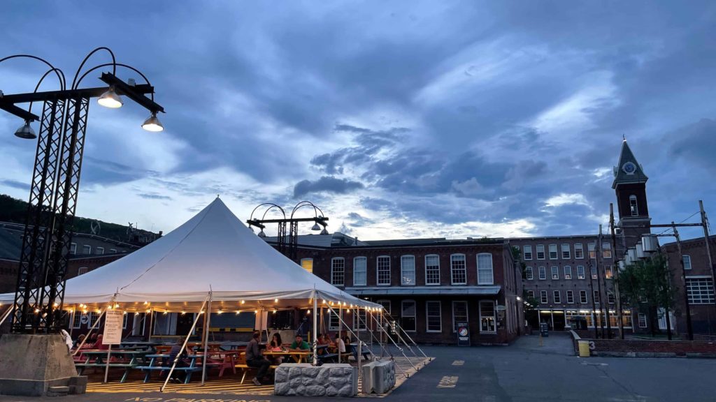 People gather among the local restaurants, taco truck and microbrewery in the Mass MoCA courtyard at night.