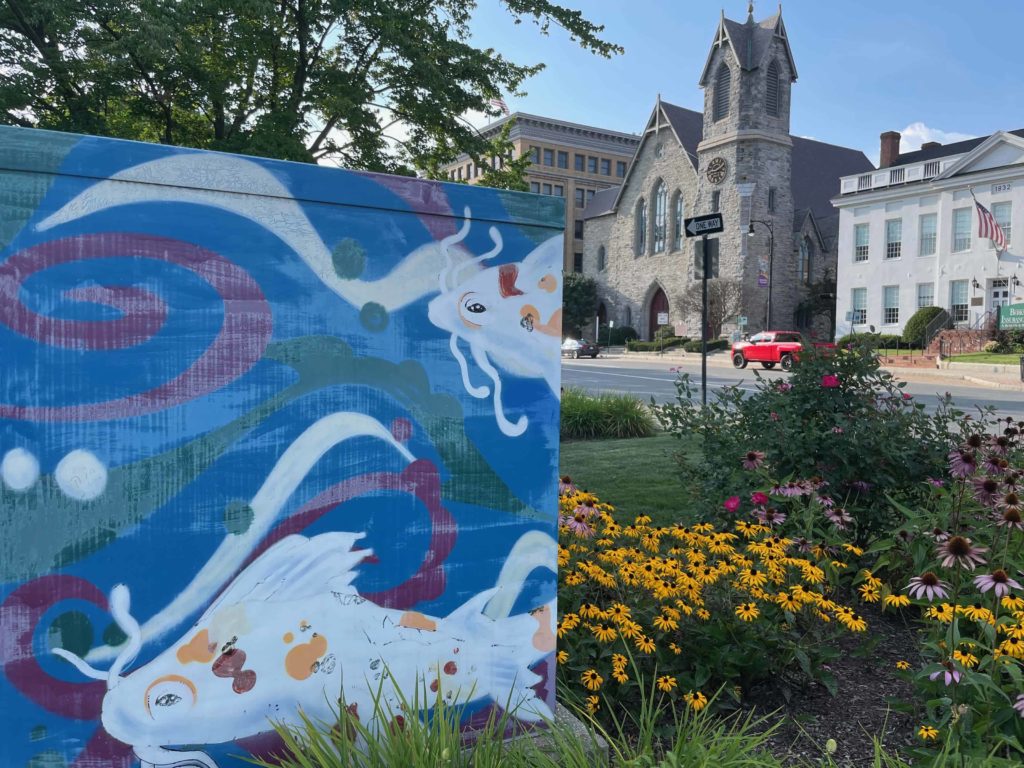 Brightly painted Koi fish swim on a transformer box in the fountain park in the downtown circle in Pittsfield.