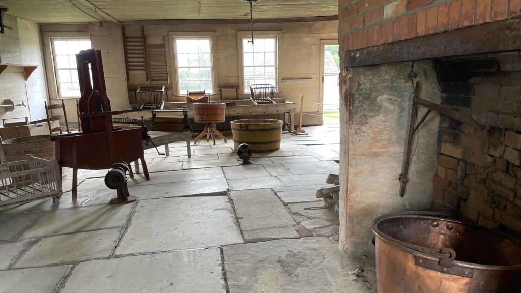 A copper kettle rests in the hearth beside the stone-paved floor of the laundry at Hancock Shaker Village.