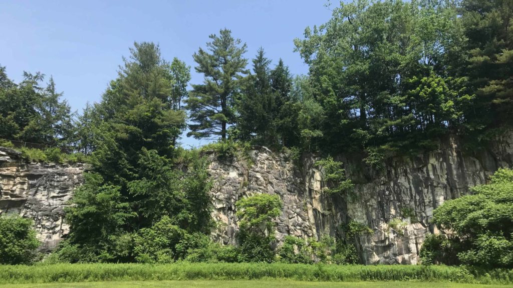 Low marble cliffs rise over the grass in Natural Bridge State Park in North Adams.