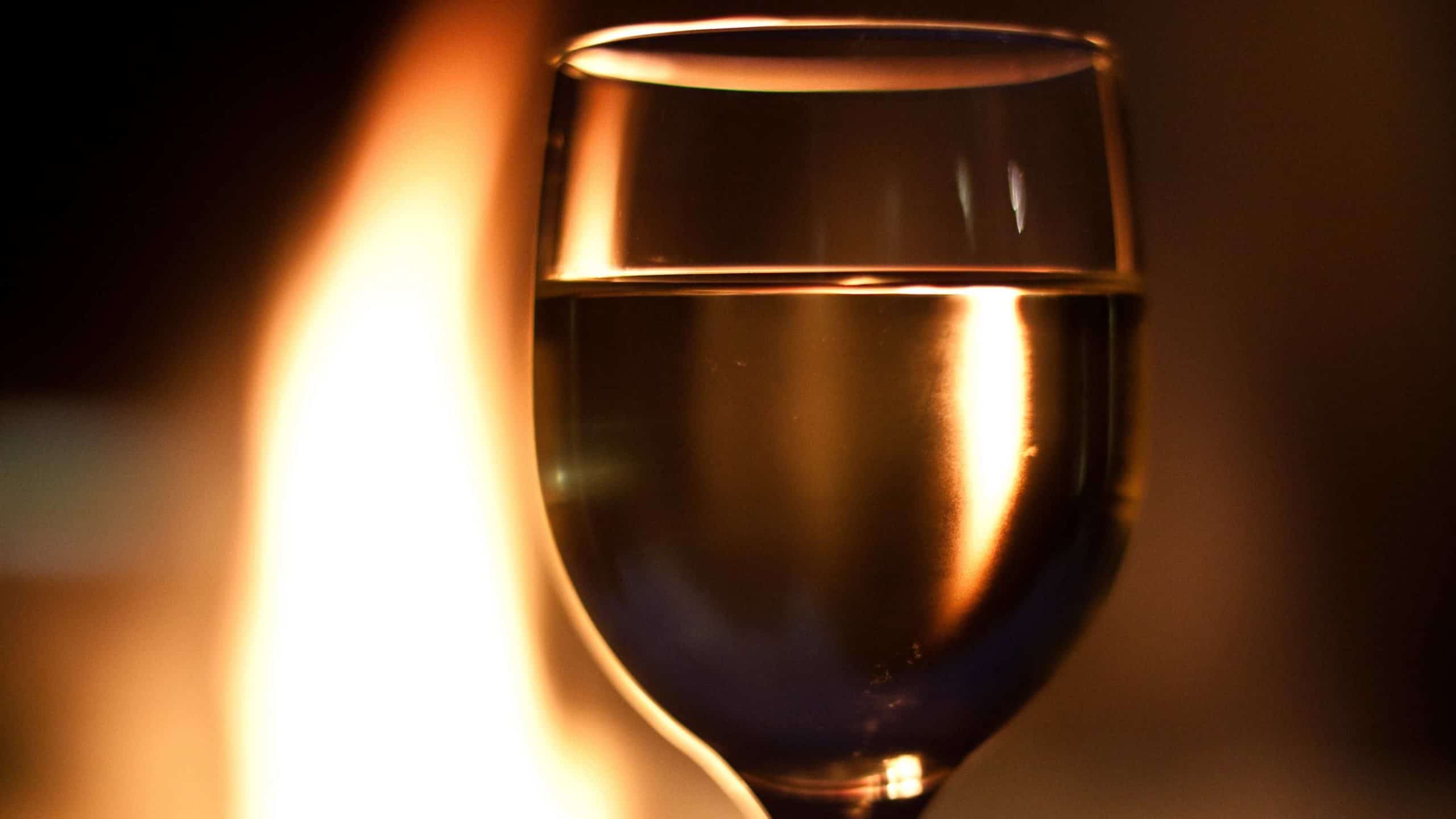 A glass of white wine glows in firelight. Creative Commons courtesy photo