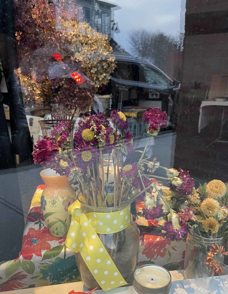 A vase of flowers stands in memory of Paula Buxbaum in the window of Bux Vintage on Spring Street.