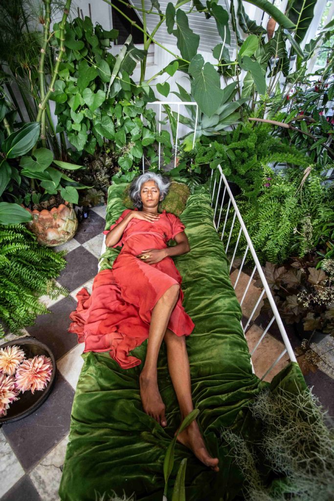 Pooja Prema lies resting among a rich array of plants in Sustenance in Rites of Passage.