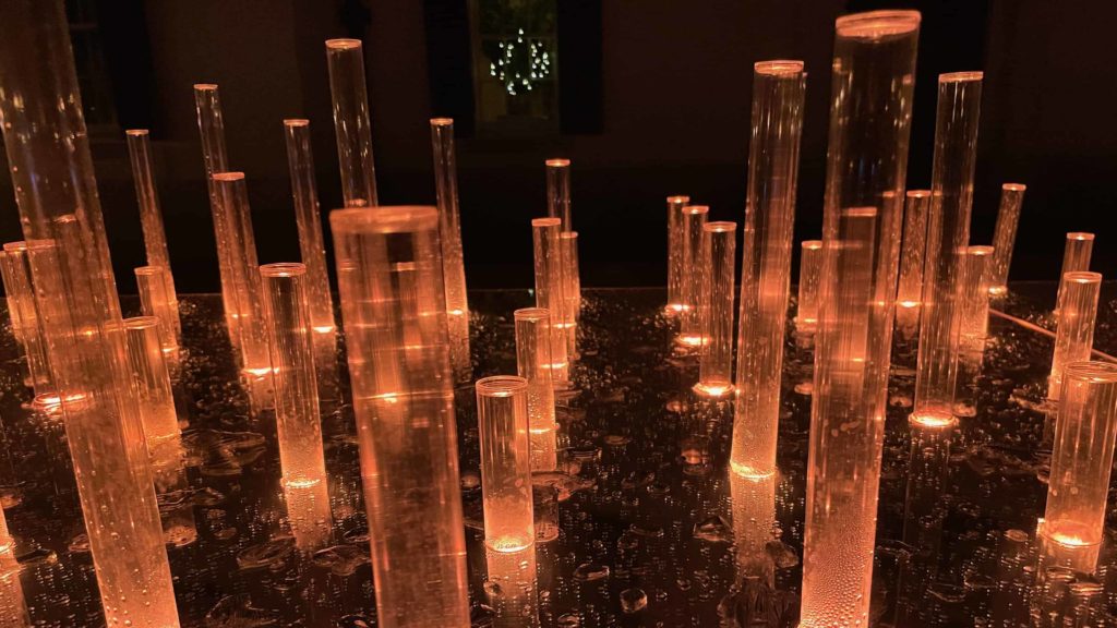 Vials of light glow on a long table in the courtyard in NightWood at the Mount.