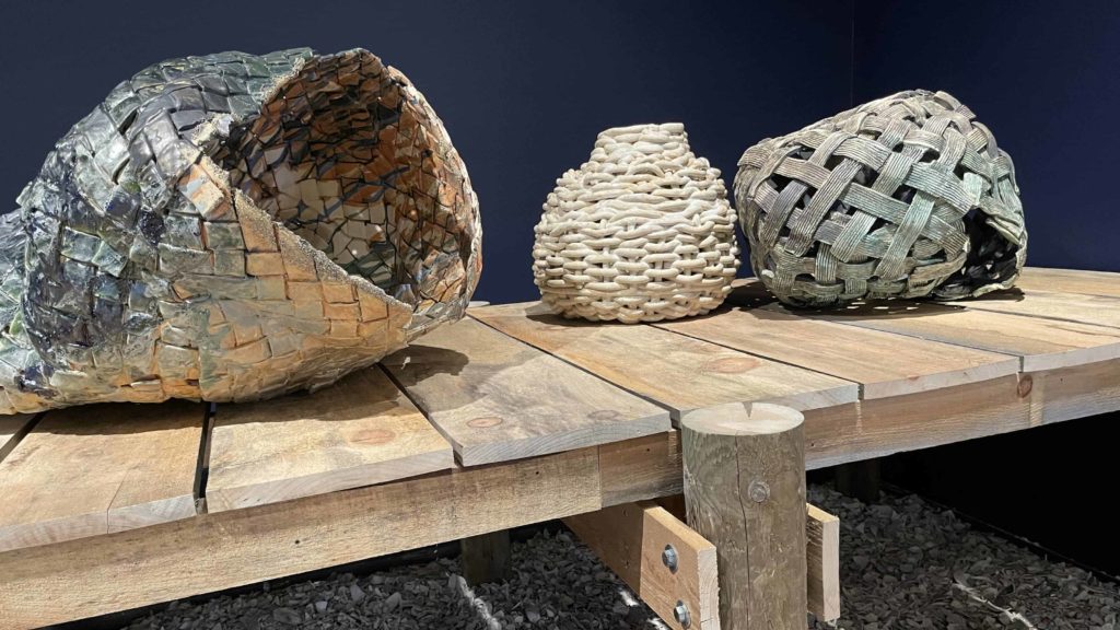 Sculptor Anina Major weaves clay into baskets on a wooden pier in 'All Us Come Across Water' at Mass MoCA.