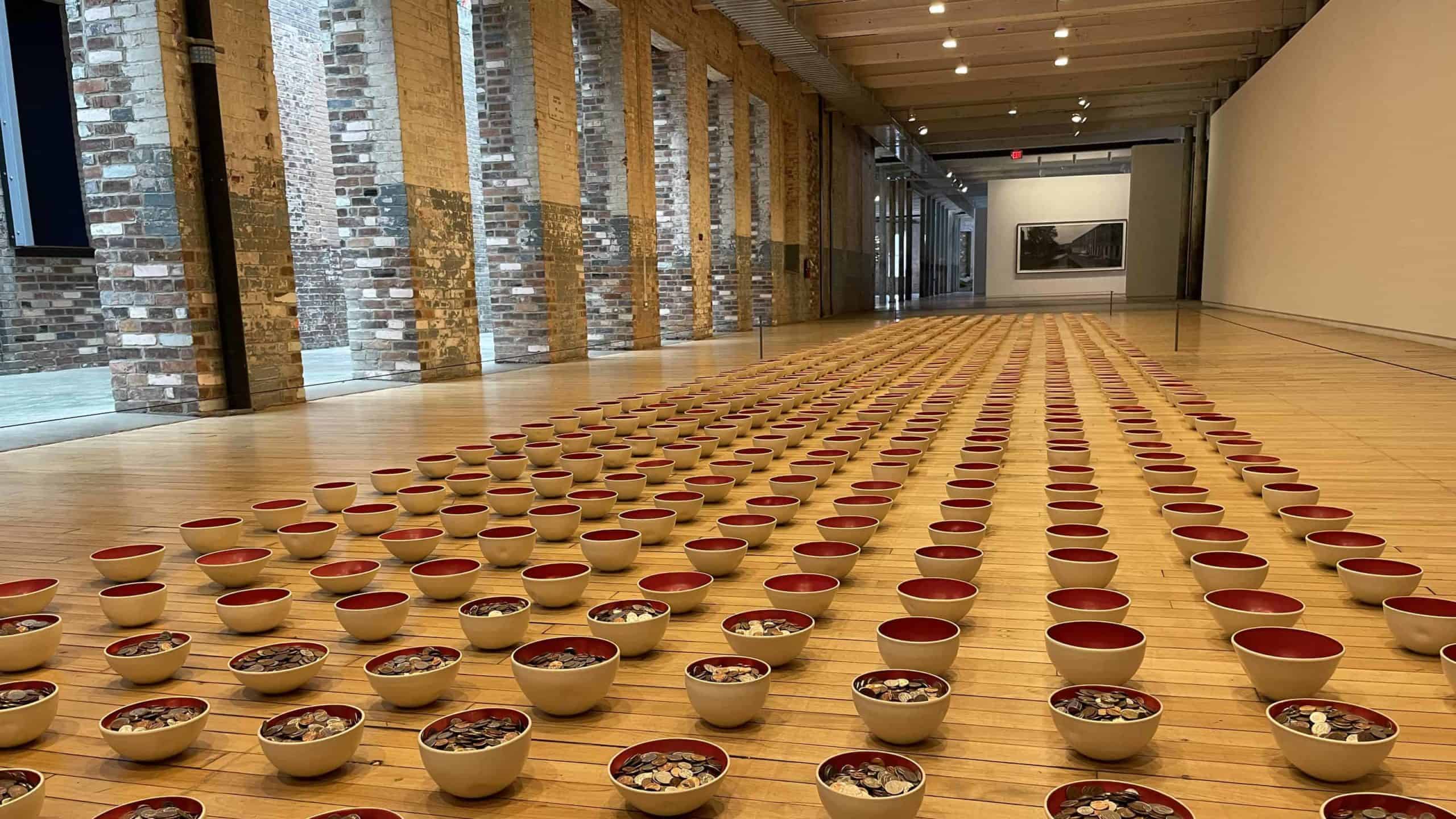 In kelli rae adams - Forever in Your Debt, bowls fill the hallway at Mass MoCA, some filled with coins and sme empty, considering the weight of student loans.