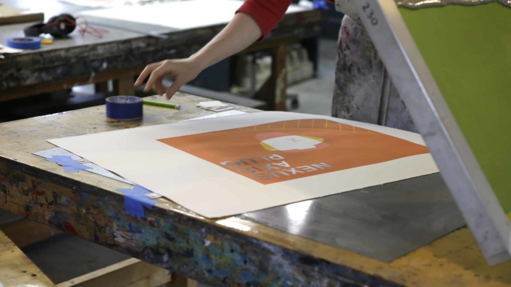 Sarah McDermott pulls a silkscreen print in orange ink in her Studio. Creative Commons courtesy photo