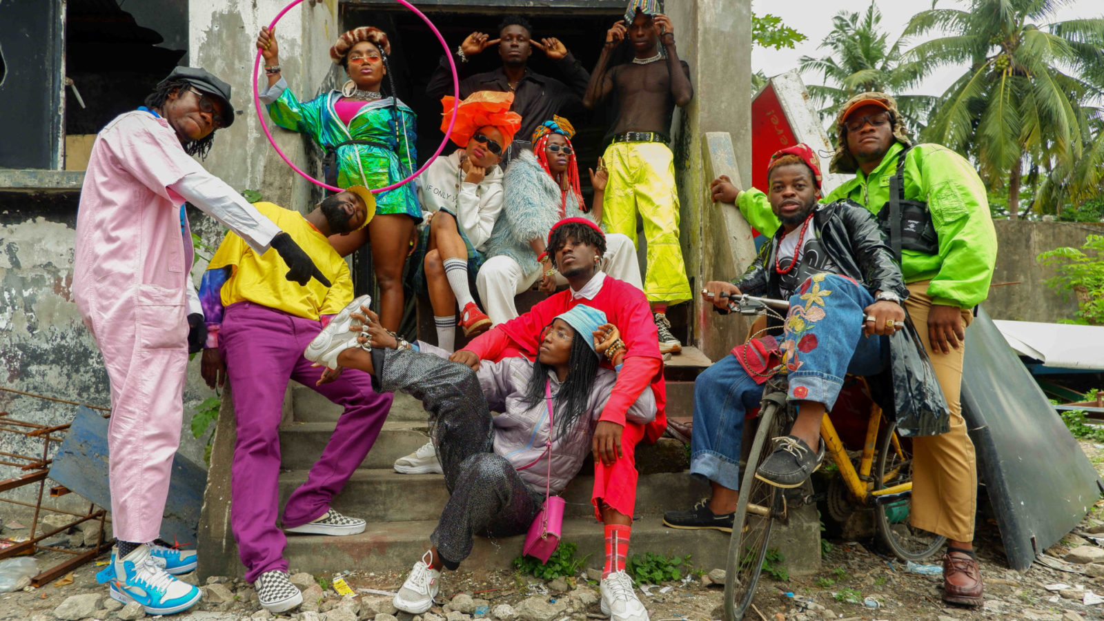 Performers from QDance Company in Lagos, Nigeria, gather on the steps of a house in brilliantly colorful contemporary clothing.