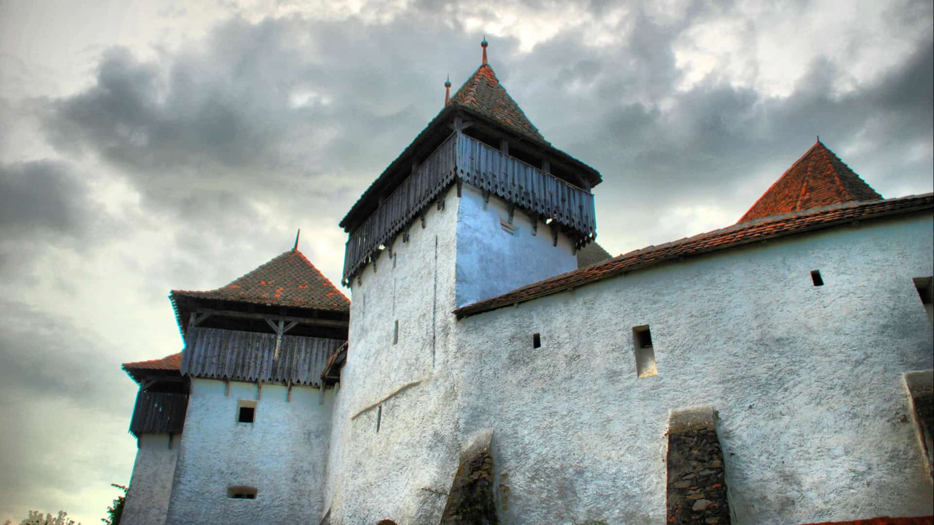 A castle in Romania lifts peaked towers toward a cloudy sky. Creative Commons courtesy photo