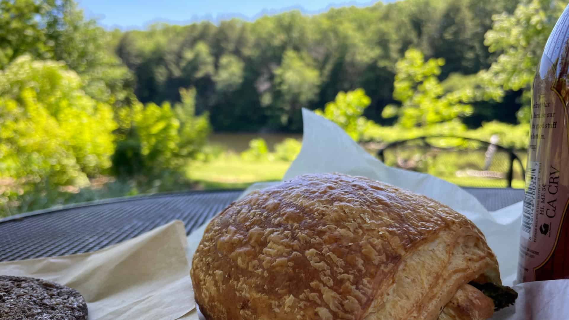 A croissant from Berkshire Mountain Bakery rests on a table in the sun on the bank of the Housatonic River.