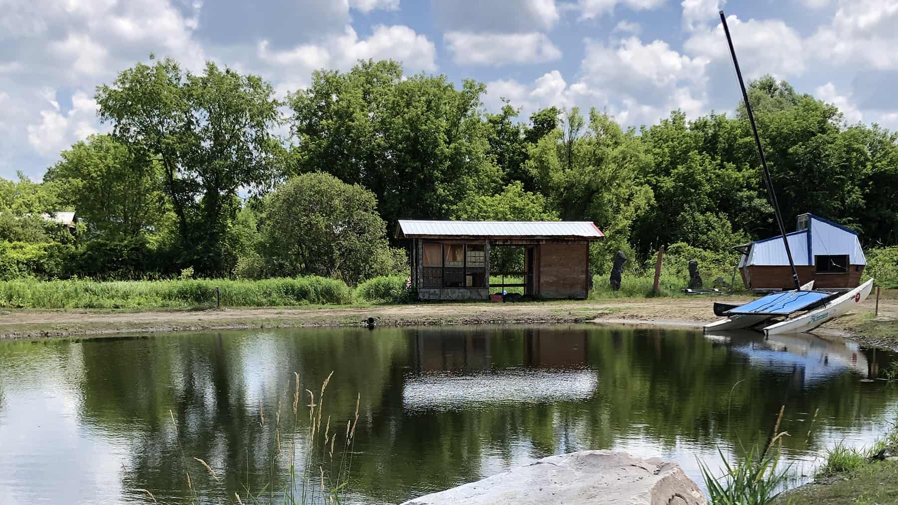 An open wooden shed sits on the shore of the pond at Salem Art Works.
