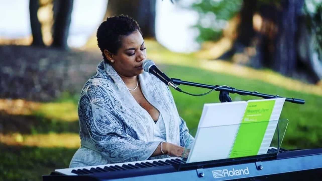 Chantell performs on keyboard outdoors in sun-dappled shade.