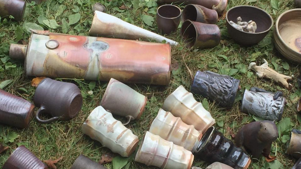 Ceramics artist Daniel Bellow's handthrown cups rest in the grass in earth tones from copper to cream to ebony. Press photo courtesy of the Holiday Shindy