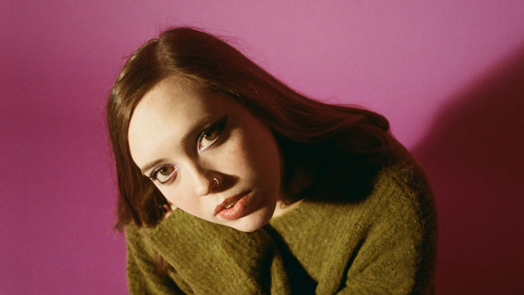 Indy rocker Soccer Mommy sits drawn in under colored light. Press photo courtesy of Mass MoCA
