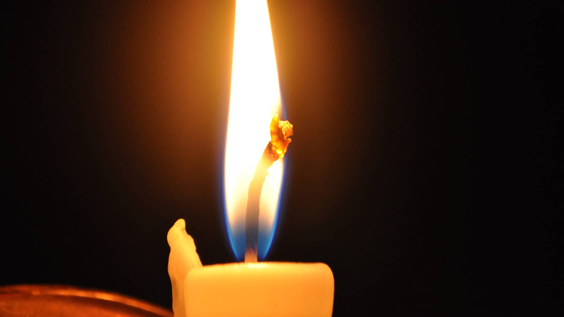 Close up, a candle flame glows blue at the base and gold at the tip. Creative Commons courtesy photo