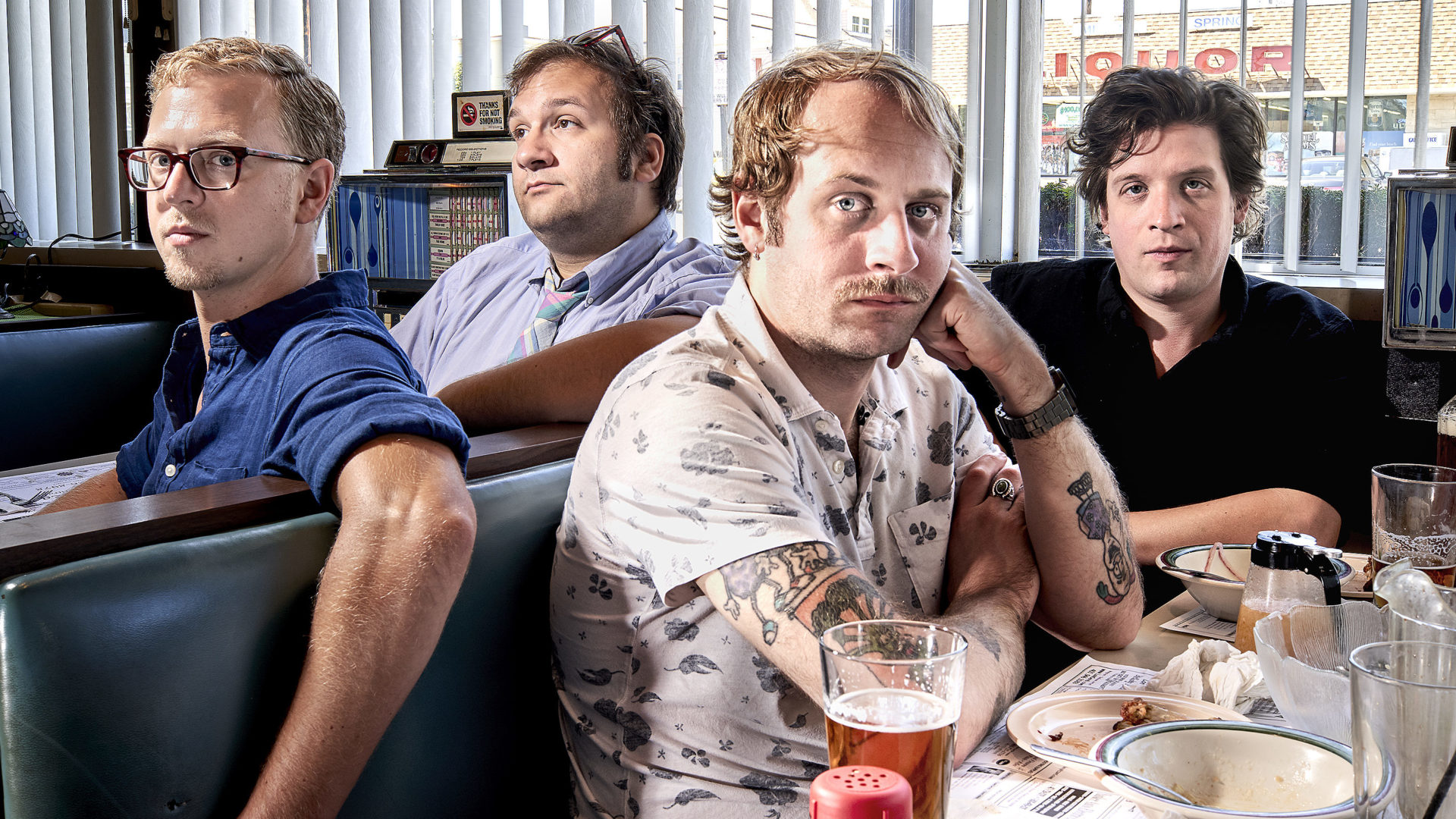 The bandmembers of Deer Tick sit around a table at a diner. Press photo courtesy of the Mahaiwe
