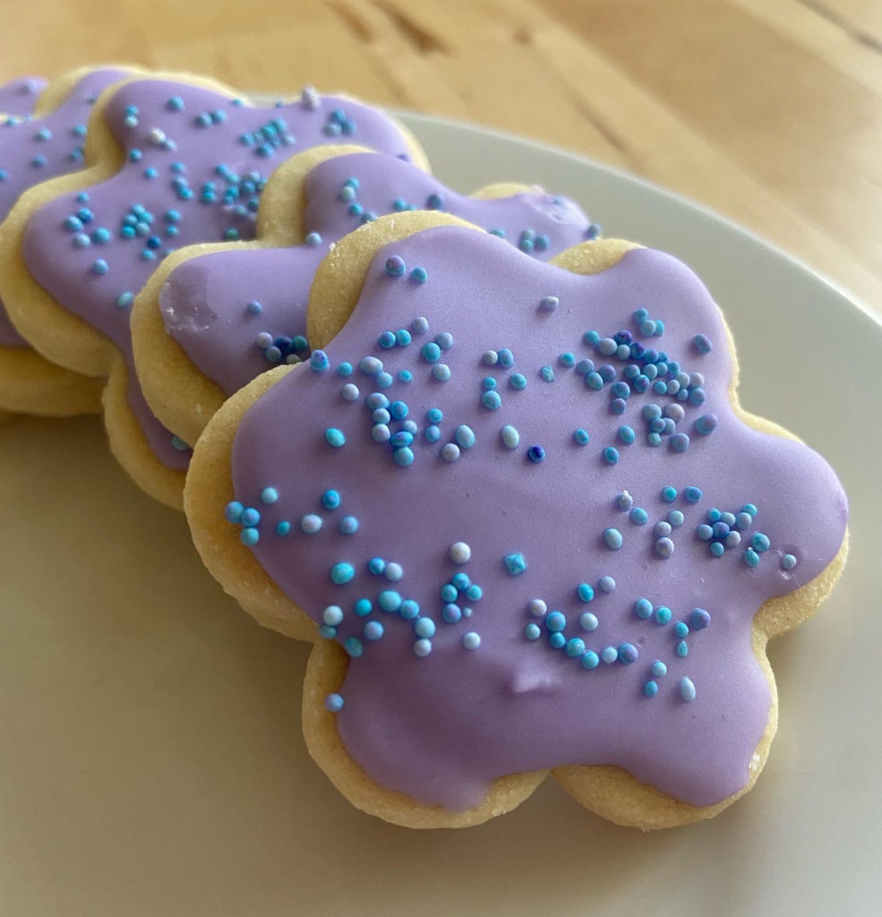 Purple flower-shaped cookies from Sweet Sam Bakes are frosted in springlike colors. Press photo courtesy of the artist